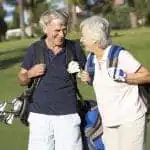 A man and woman holding golf bags at a 55+ community in huntington beach called huntington landmark.