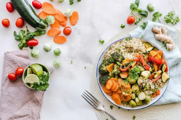 Colorful vegetable stir-fry with quinoa, fresh herbs, and ginger on a white background.