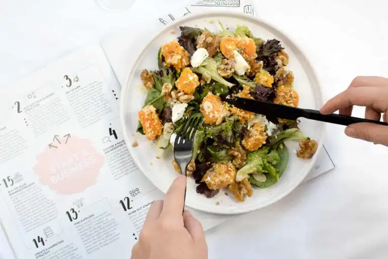 Healthy salad with greens, cheese, and nuts on a white plate.